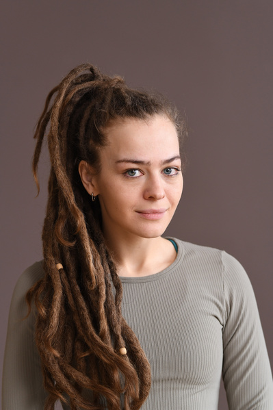 Portrait of a young athletic woman with dreadlocks in a beige sports top