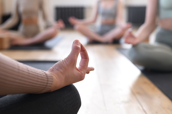 A woman doing mudra of knowledge in the lotus position in a group yoga practice