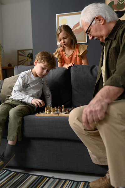 A little blond boy making a move while playing chess with his grandfather