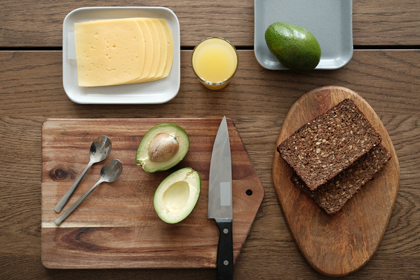 Top view of the products for a hearty breakfast with bread and avocado laid out on a wooden table