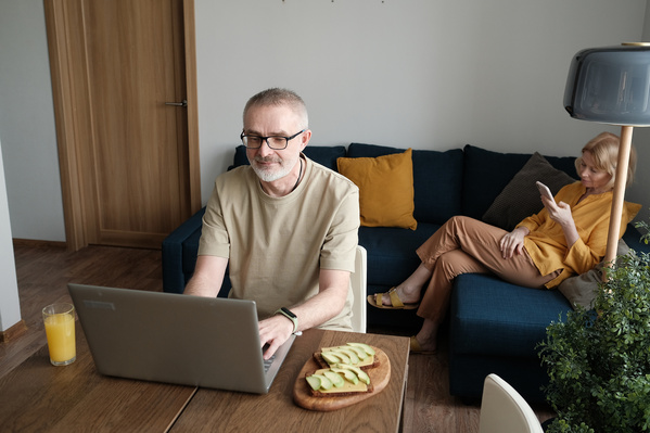 A man in glasses using a silver laptop at an avocado toast breakfast