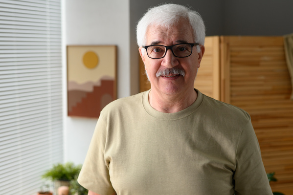 Portrait of an elderly man with a beard in glasses and a light T-shirt