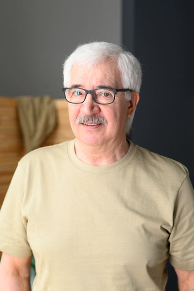 Portrait of a smiling elderly man with a beard glasses and a light T-shirt