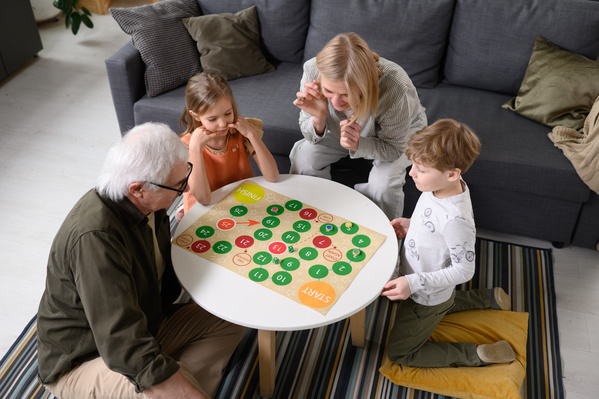 Little kids playing a bright board game with their elderly grandparents in their house