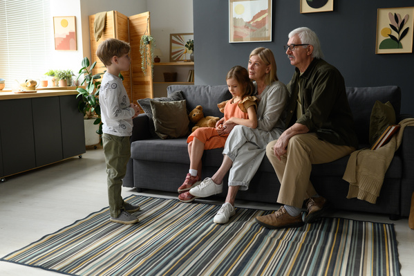 Elderly grandparents with blond hair communicating with their grandchildren in a bright living room
