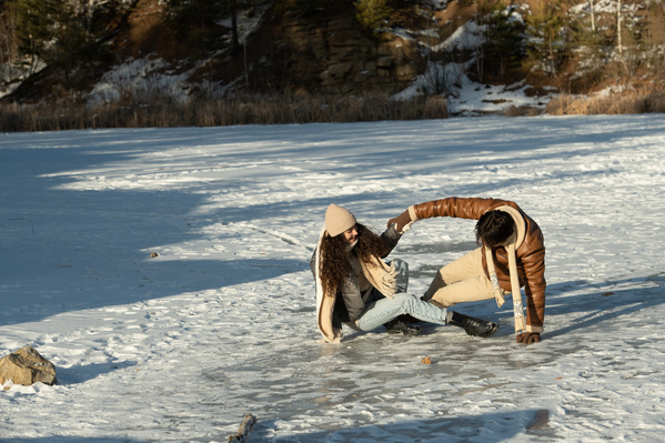 Romantic couple in warm winter clothes amusing themselves on a frozen lake