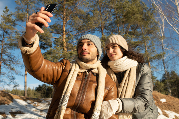 A man in warm clothes taking a selfie with his girlfriend on a winter date
