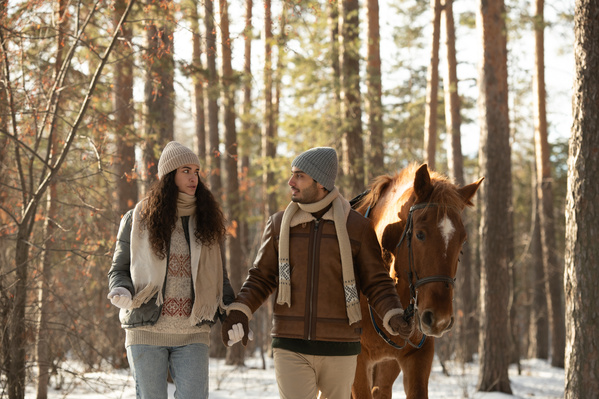 A Couple Walking with a Horse in the Winter Forest