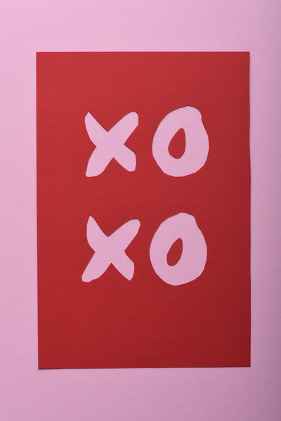 A romantic red postcard lying on a matte pink surface