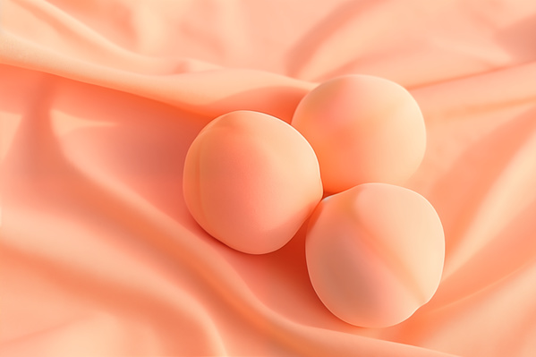 Three Eggs Laying on Top of a Peach Colored Sheet of Cloth