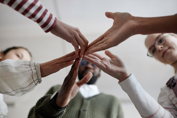 In this image a group of people are gathered together with their hands stacked on top of each other forming a pyramid-like structure.