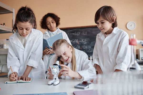 A Group of Kids in Lab Coats Looking at a Toy