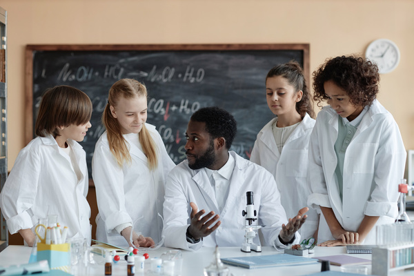 A Group of People in White Lab Coats Standing around a Table Talking