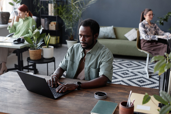 An African American Man Working on a Laptop in an Office