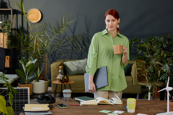 A Woman in a Green Shirt Standing in Front of a Desk