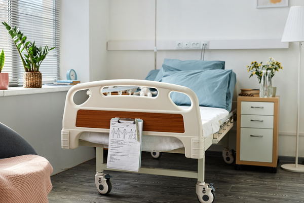 The image depicts a hospital room with a hospital bed in the center of the room.