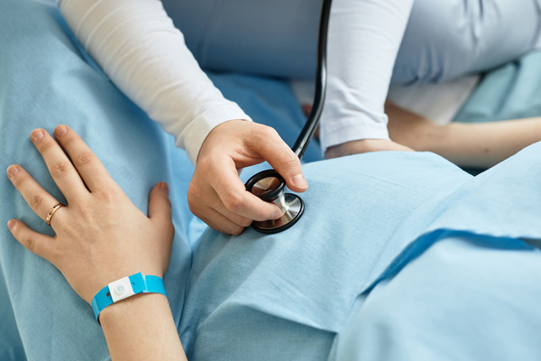 A Person Using a Stethoscope on a Pregnant Woman