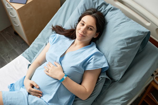 In this image a pregnant woman is lying down in a hospital bed.