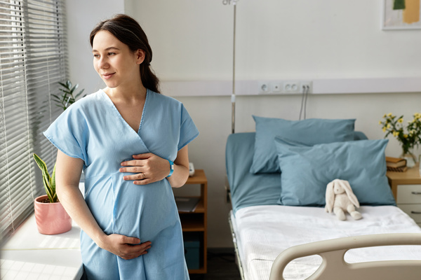 A Pregnant Woman Holding Her Stomach in a Hospital Room