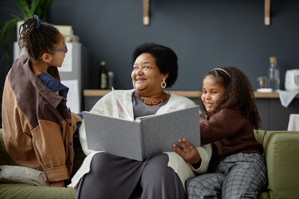 A Woman Sitting on a Couch with Two Children Looking at a Book