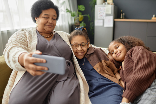 In this image a woman and two young girls are sitting on a couch together enjoying each other's company.