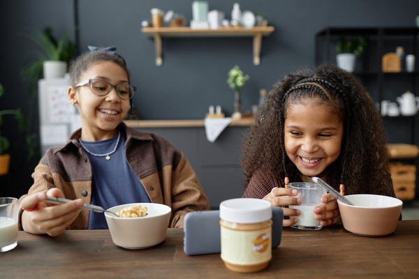 Two Kids Sitting at a Table with Bowls of Cereal