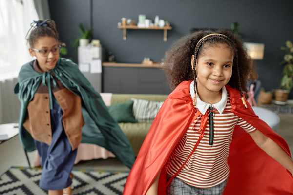Two Young Girls Dressed up As Superheroes in a Living Room
